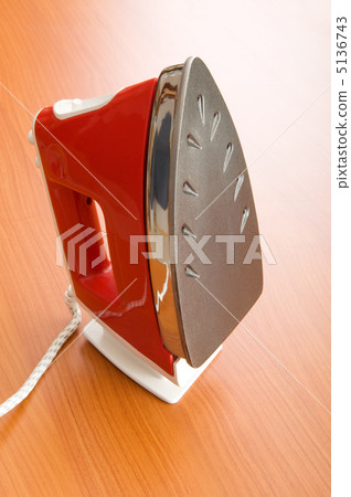 Modern electric iron on the wooden background Modern electric iron on the wooden background 5136743