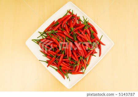 Hot peppers in the plate on wooden table 5143787