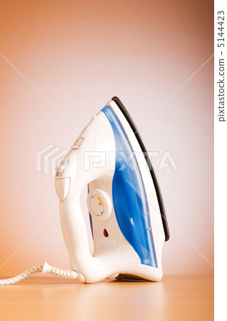 Modern electric iron against the colorful background 5144423