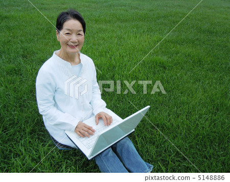 Senior female side camera looking at PC on the grass 5148886