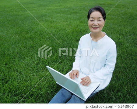 Senior female camera looking at PC on lawn Senior female camera looking at PC on lawn 5148907