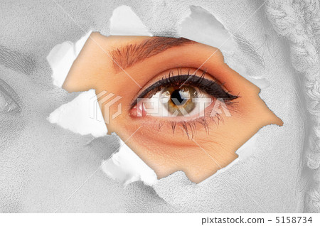 Woman eye through hole in paper 5158734