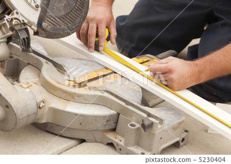 Contractor Measuring for Cutting New Baseboard for Renovation 5230404