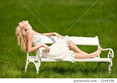 Spring - Young woman relaxing on bench in meadow Spring - Young woman relaxing on bench in meadow 5244296