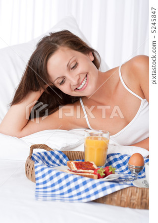 Happy woman in white bed having breakfast Happy woman in white bed having breakfast 5245847
