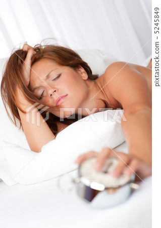 White lounge - Tired woman holding alarm clock White lounge - Tired woman holding alarm clock 5245849