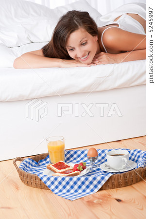 Smiling woman in bed watching homemade breakfast Smiling woman in bed watching homemade breakfast 5245997