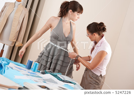 Female fashion designer measuring model for fitting 5247226