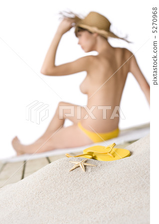 Beach - starfish with flip-flop on sand, woman in background 5270968