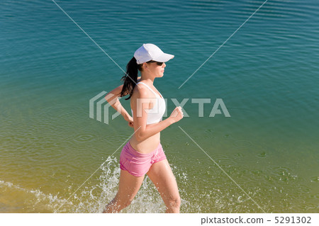 Summer sport fit woman jogging along seashore Summer sport fit woman jogging along seashore 5291302