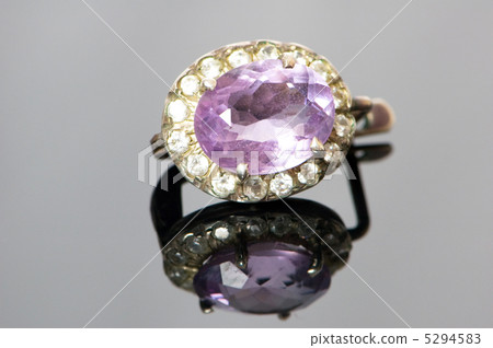 Ring with purple stone on reflective background Ring with purple stone on reflective background 5294583