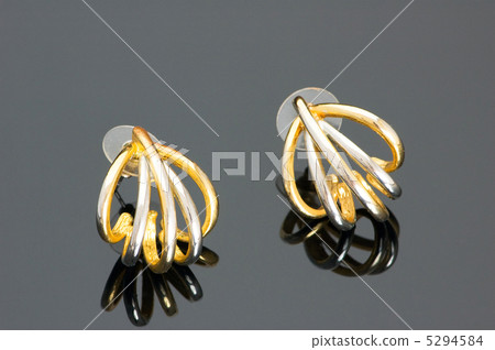 Pair of golden earrings on black reflective surface Pair of golden earrings on black reflective surface 5294584