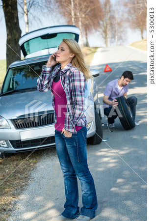 Woman calling for car assistance change wheel 5300013