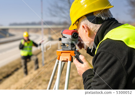 Geodesist measure land with tacheometer highway 5300052