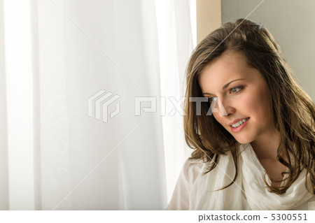 Thoughtful brunette woman looking out of window 5300551