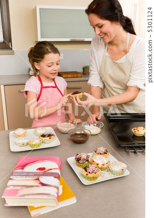Daughter and mother decorating cupcakes sprinkles Daughter and mother decorating cupcakes sprinkles 5301124