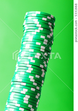 Stack of green casino chips against green background 5331668