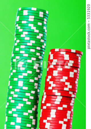 Stack of red and green casino chips against green background 5331920