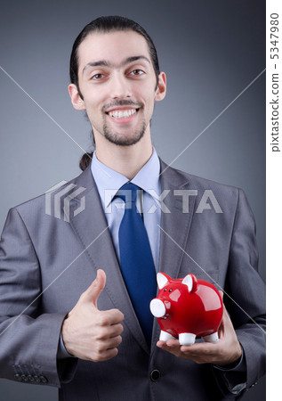 Man with piggybank on grey Man with piggybank on grey 5347980