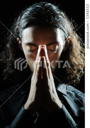 Young man praying in darkness Young man praying in darkness 5348553