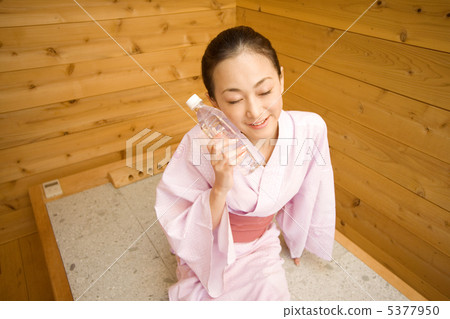 把塑料瓶放的婦女在她的面頰在沐浴岩石以後 5377950