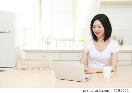 A woman watching a computer in the kitchen 5391921