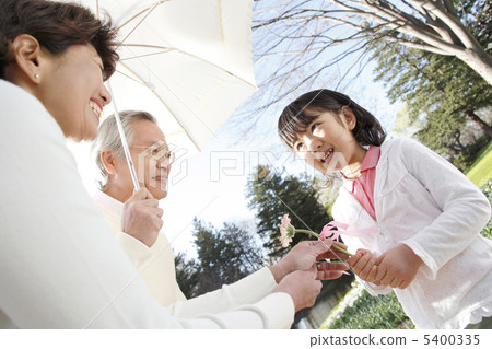 A girl trying to hand flowers to grandparents 5400335