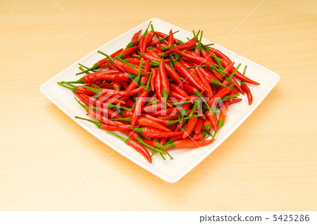 Hot peppers in the plate on wooden table Hot peppers in the plate on wooden table 5425286