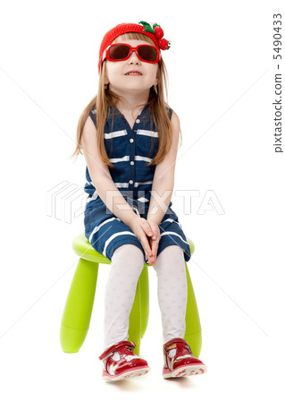 little girl in a red hat and sunglasses sitting on a green chair 5490433