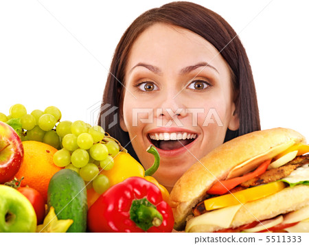 Woman choosing between fruit and hamburger. 5511333
