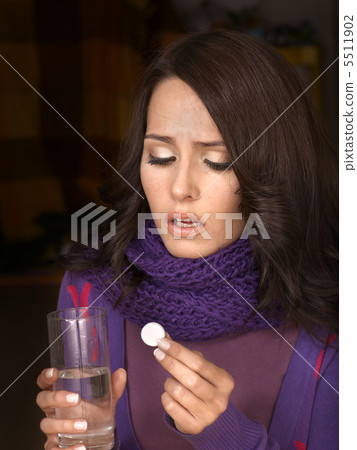 Girl holding glass of water and taking pills. 5511902