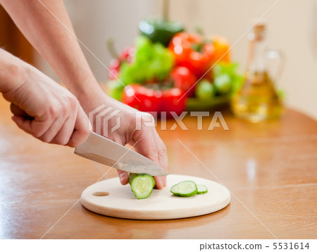 Cutting of cucumer on hardboard and fresh vegetables on backgrou Cutting of cucumer on hardboard and fresh vegetables on backgrou 5531614