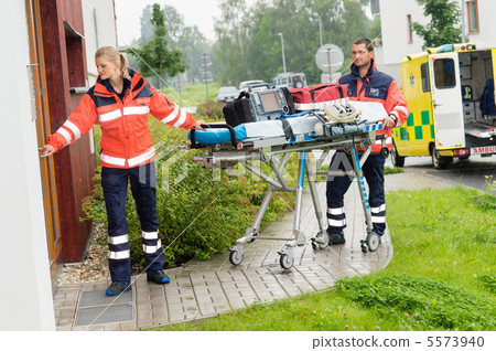 Paramedics carrying stretcher ambulance house call 5573940
