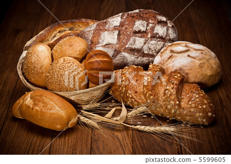 各種各樣在一張木桌上的新近地被烘烤的麵包 5599605