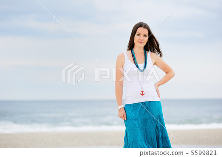Beautiful young woman stands against ocean 5599821