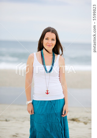 Beautiful young woman stands against ocean 5599823