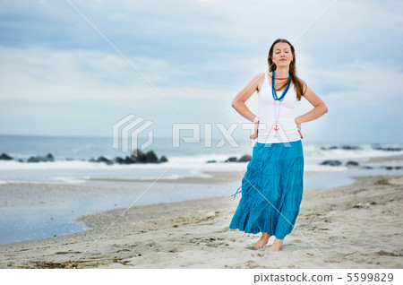 Beautiful young woman stands against ocean 5599829