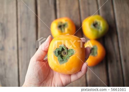 一名女子的左手拿著一個無籽柿子 5661081