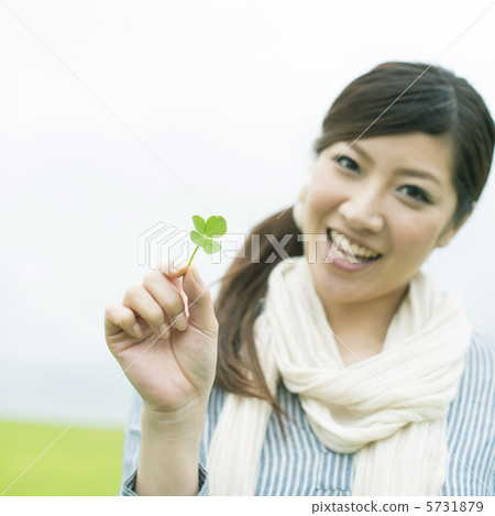 A woman holding a four-leaf clover and a smile at the meadow A woman holding a four-leaf clover and a smile at the meadow 5731879