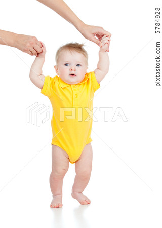 First steps of baby with help of mothers hands First steps of baby with help of mothers hands 5784928