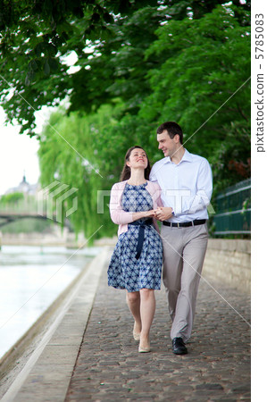 Happy positive couple is walking together by the Seine Happy positive couple is walking together by the Seine 5785083