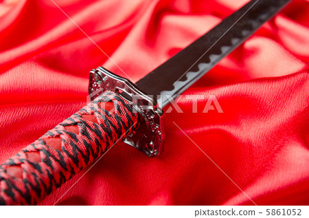 Japanese sword takana on red satin background Japanese sword takana on red satin background 5861052
