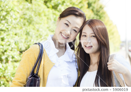 Mother and daughter walking together on the sidewalk 5906019