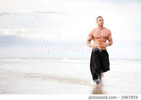 Young man running along a beach 5967859