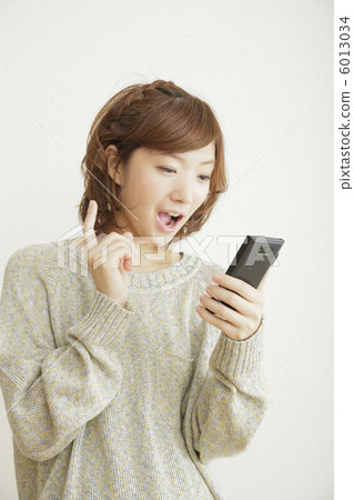 Woman operating a smartphone Woman operating a smartphone 6013034