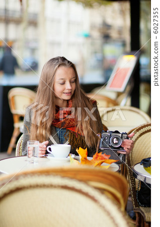 Beautiful young woman in a cafe holding an old-fashioned photo c 6027355