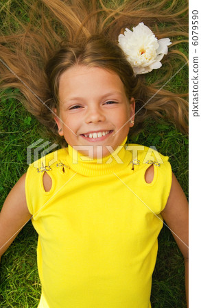 Happy young girl lying on a green grass Happy young girl lying on a green grass 6079590