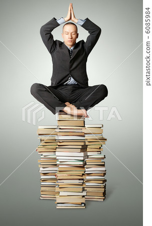 businessman in lotus pose with many books near 6085984