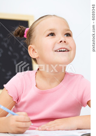 Little girl is writing using a pen Little girl is writing using a pen 6089348