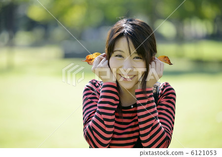 A woman who puts fallen leaves on her ear A woman who puts fallen leaves on her ear 6121053